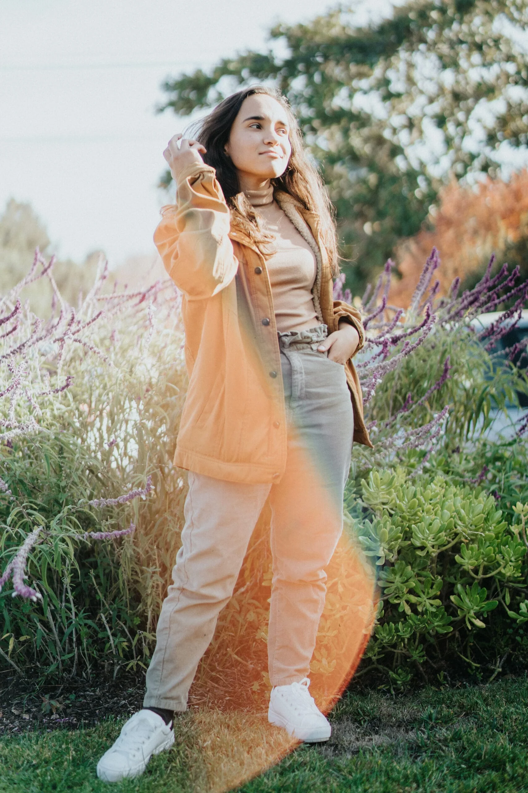 A woman, dressed in a tan jacket and khaki pants, skillfully captures beautiful moments in a field as a family photographer or luxury photography services provider.