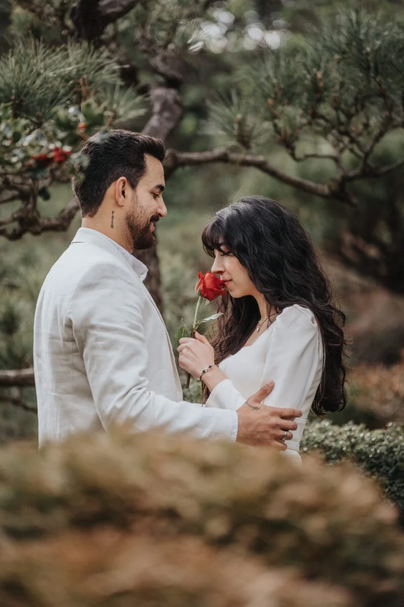 Japanese couple in a garden holding a red rose captured by a San Francisco photography.